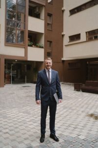 Businessman in formal suit with laptop outside an office building.